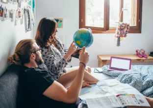 couple faisant des plans de voyage au lit en tenant un globe terrestre